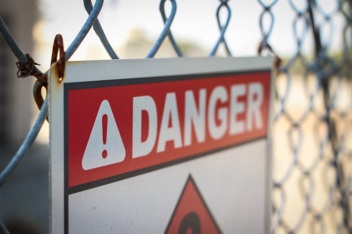 danger sign on a wall fence representing the list of outsourcing risks