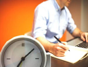 a clock and a man writing