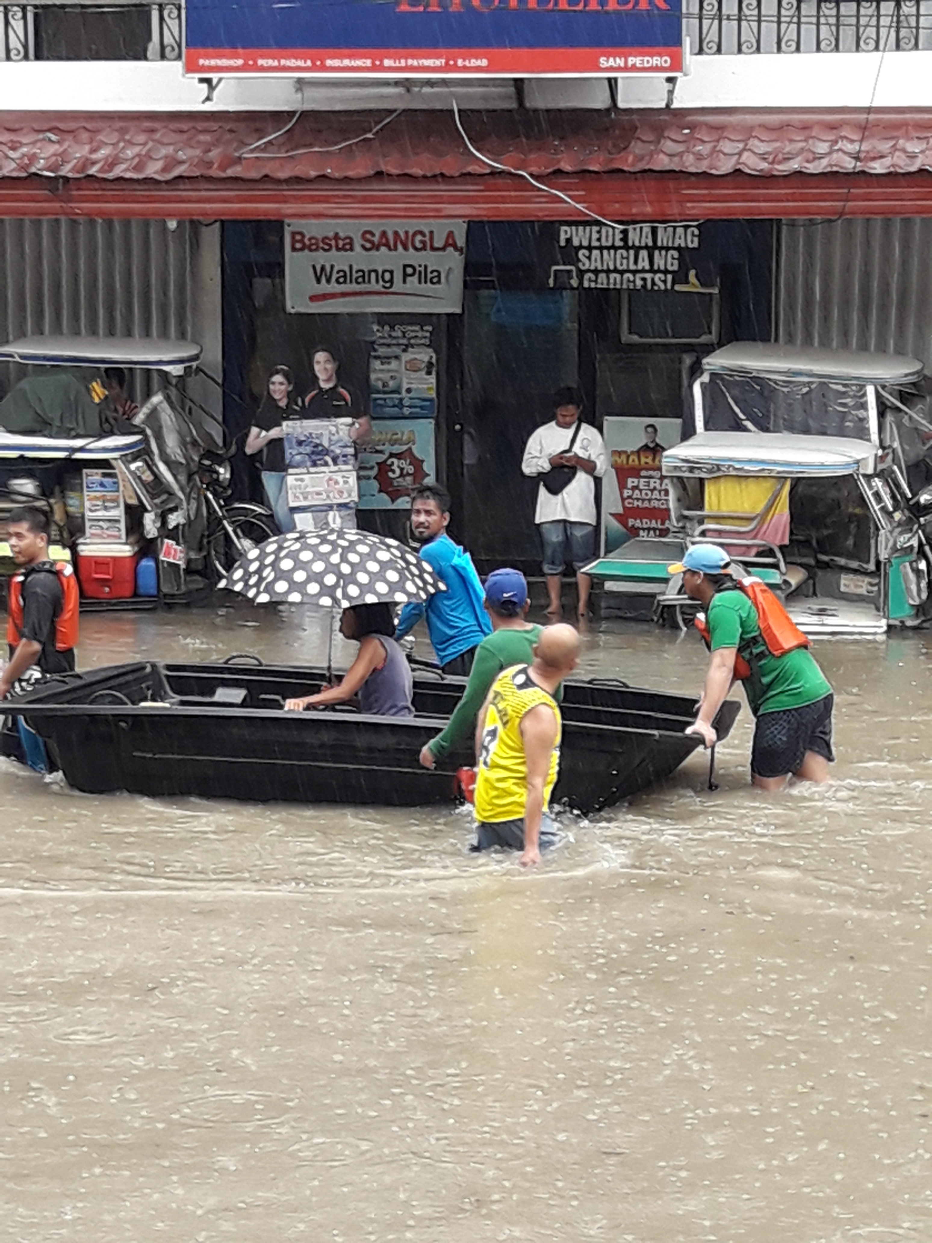 Commuters ride a make-shift boat so they can cross the flooded roads