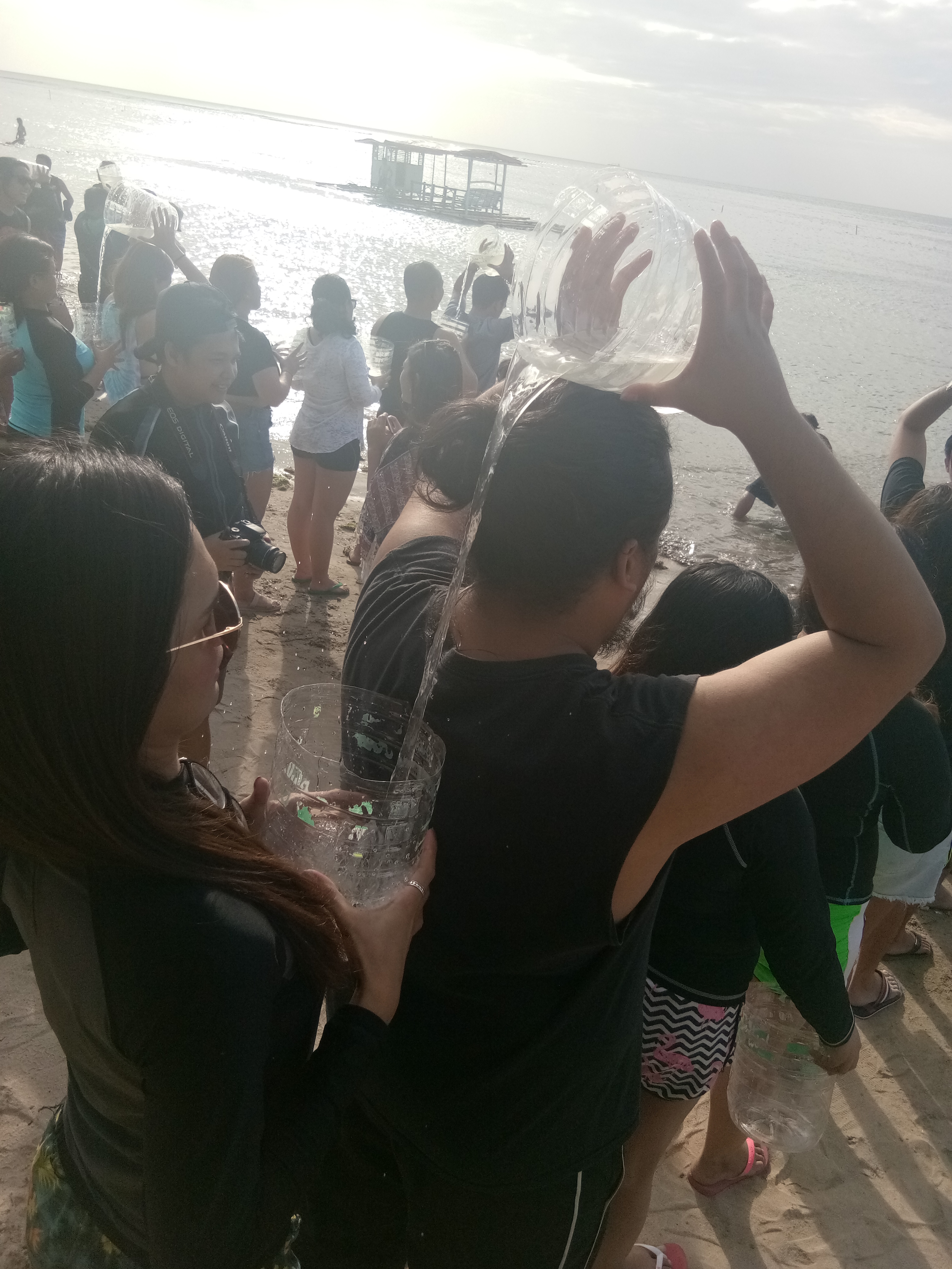 A player pours water into another player in the Water Relay Game