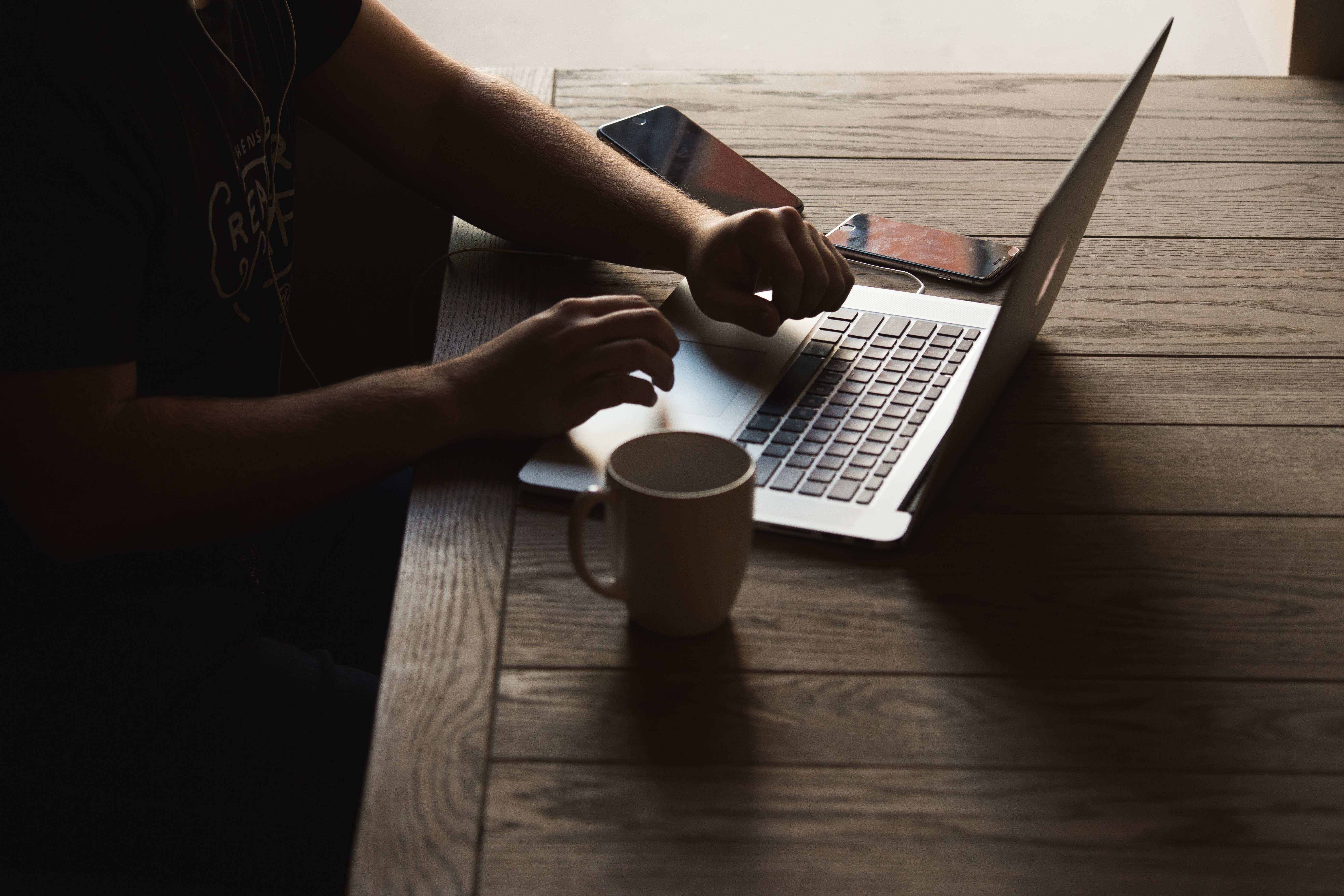 a man typing in his laptop on top of a brown table - copywriting tips