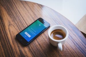 Twitter's welcome message on iPhone and a cup of coffee before following digital marketing experts on twitter