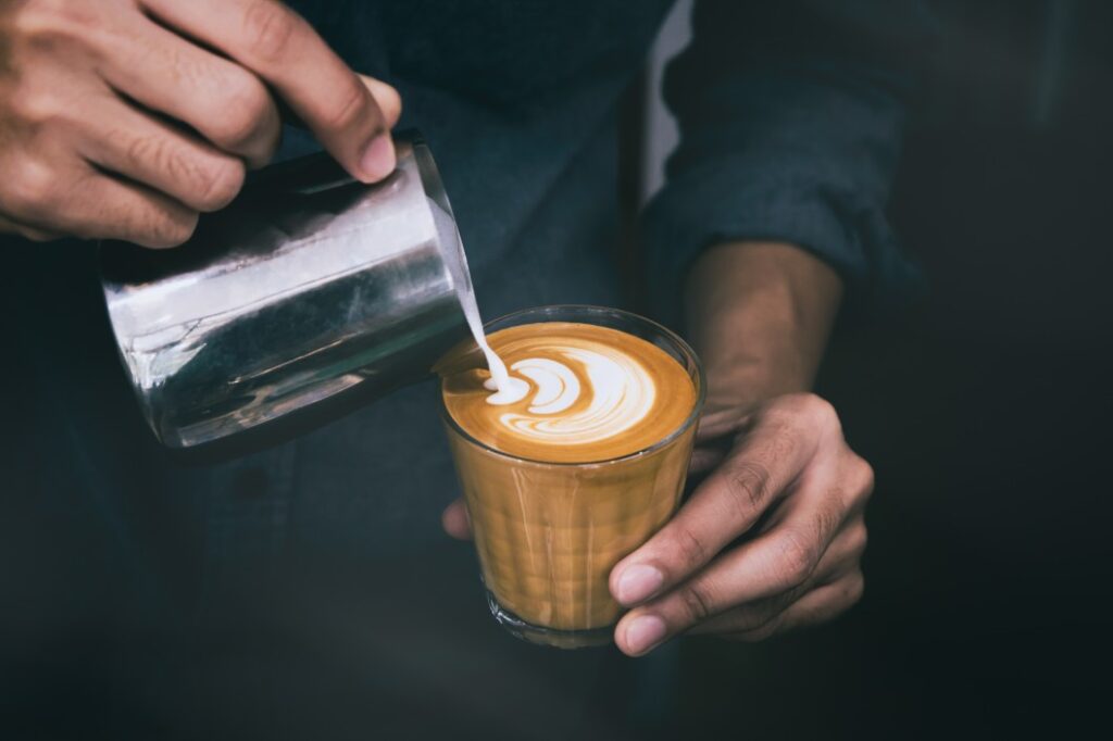 barista pouring milk to coffee for latte art