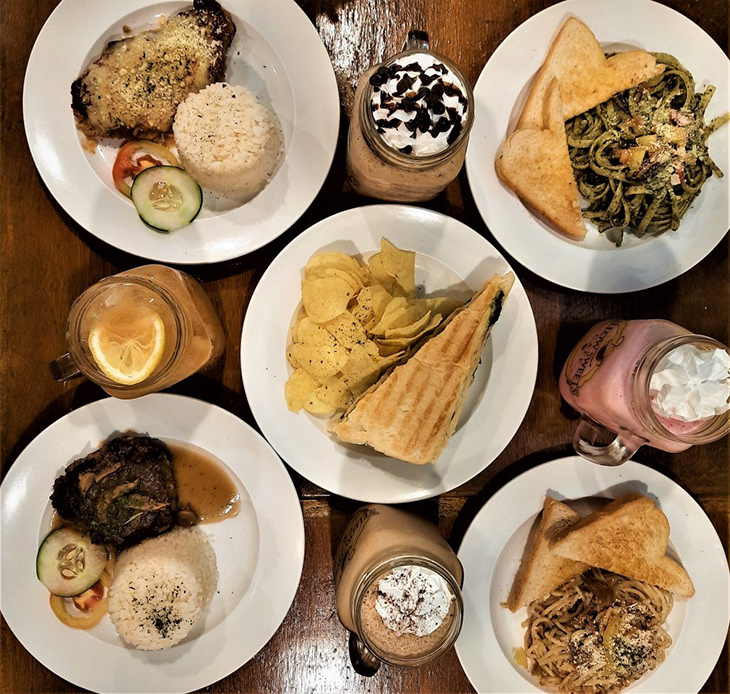 Flat lay of panini with chips, chicken parmigiana, Salisbury steak, pasta, and drinks