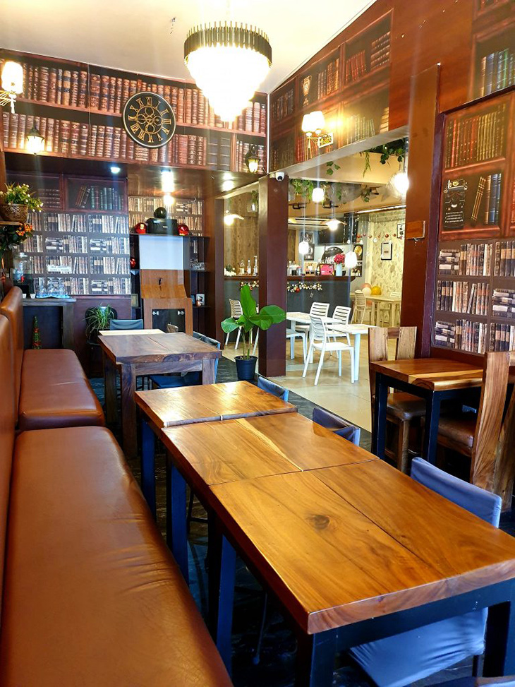 Room with book wallpaper, chairs and long tables, and plant accent.