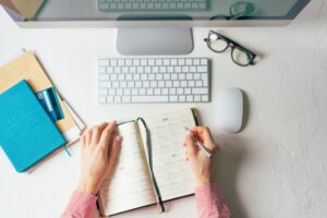 Woman writing steps of career planning process to achieve professional goals on her notebook.