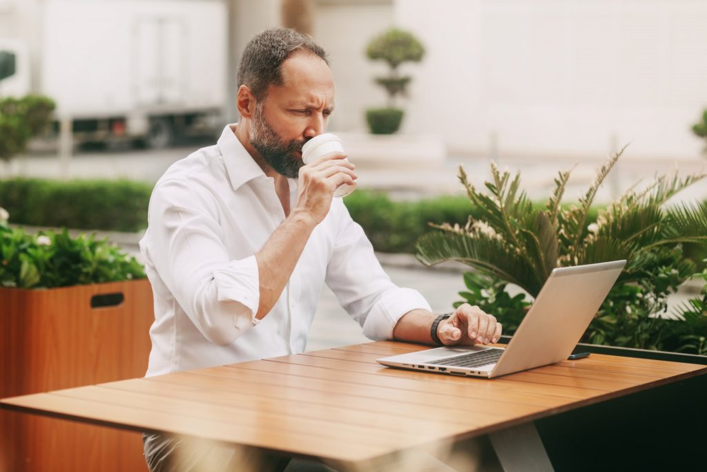 male businessman sitting on the street in a cafe looking to hire a virtual assistant