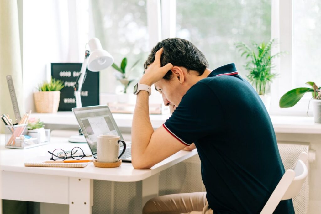employee holding his head and closing his eyes from headache due to work stress