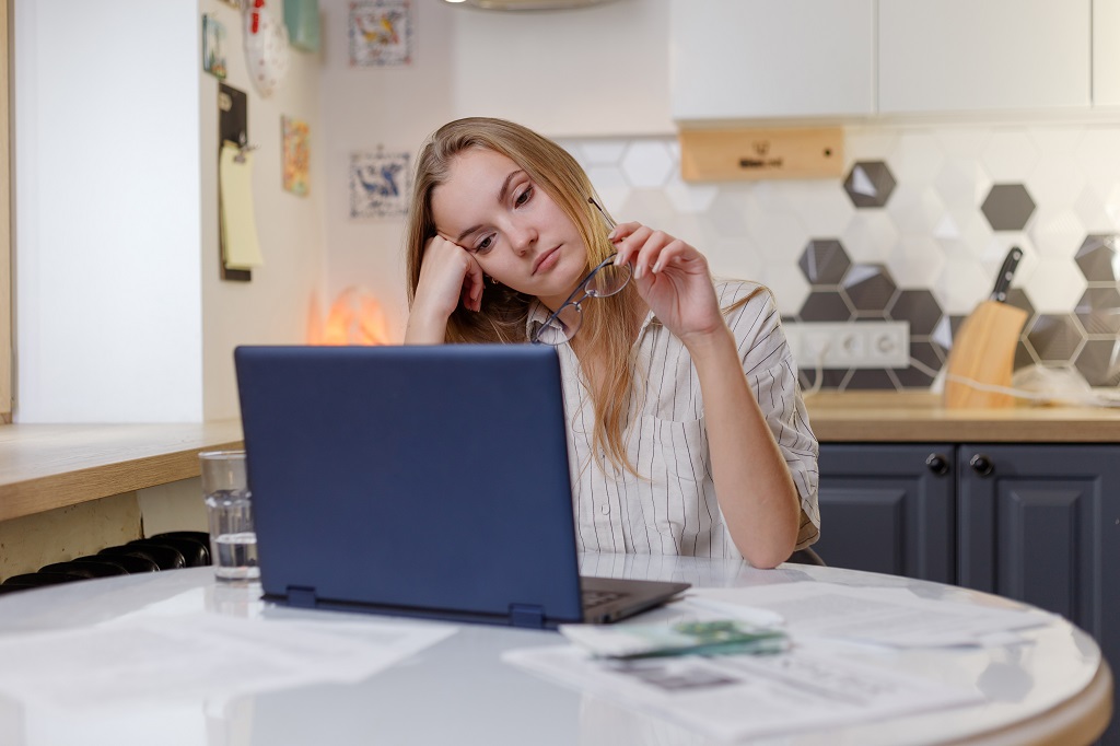 a female employee working from home, showing a lack of engagement and interest in her tasks