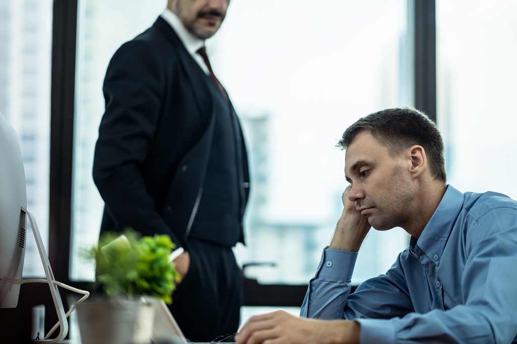 an unmotivated employee coasting at work, staring at his computer screen without enthusiasm.